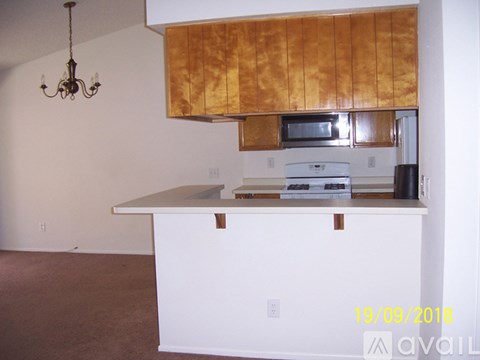 A kitchen with a white counter and a wooden hood.