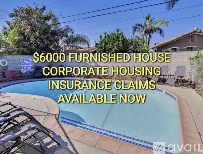A pool surrounded by palm trees and a sign advertising furnished rental corporate housing.