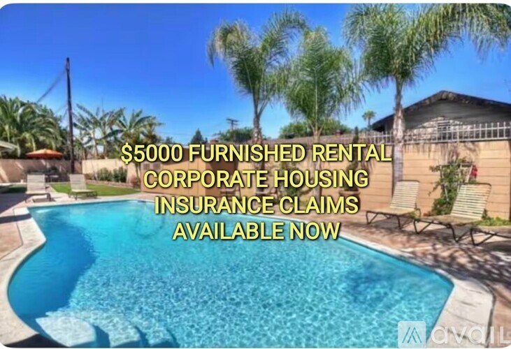 A pool surrounded by palm trees and a sign advertising furnished rental corporate housing.