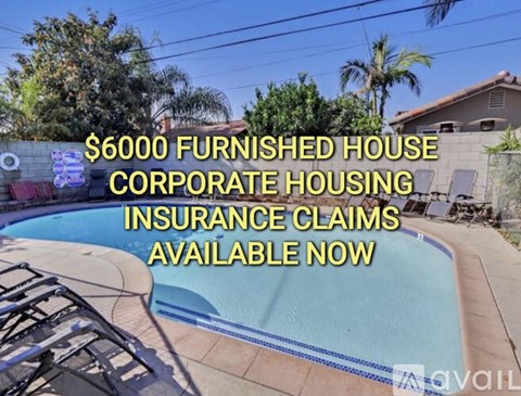 A pool surrounded by palm trees and a sign advertising furnished rental corporate housing.