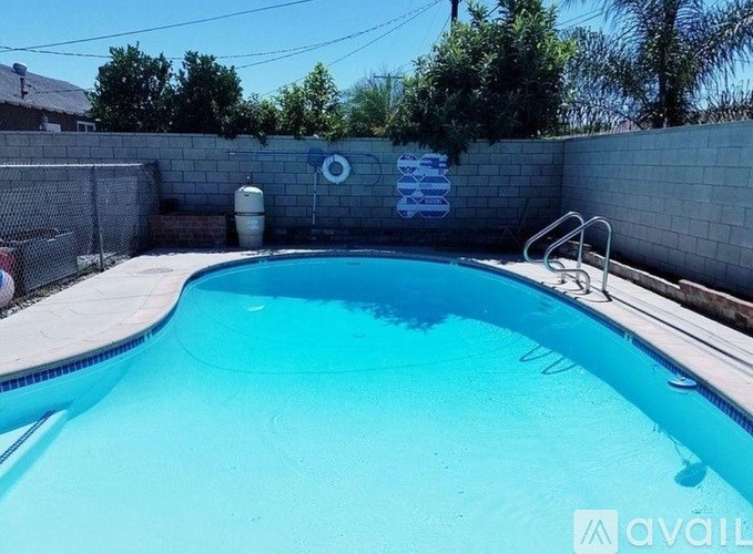 A pool with a blue tinted water and a white fence around it.