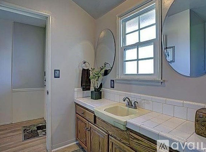 A bathroom with a sink, mirror, and a window.