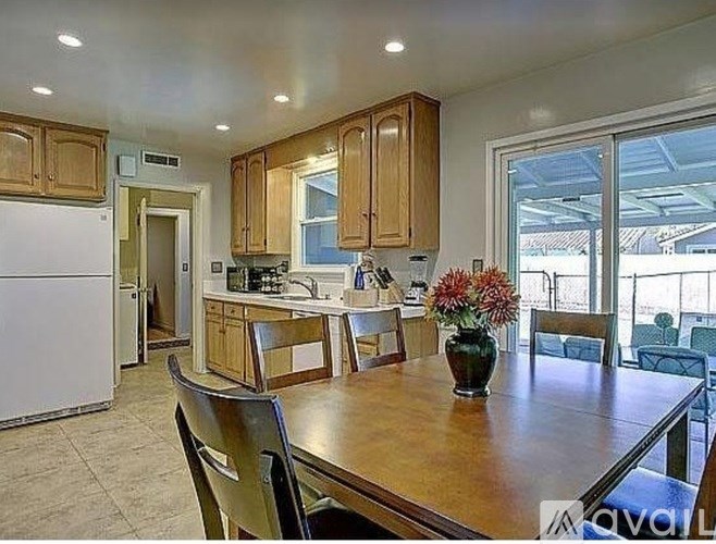 A kitchen with wooden cabinets and a table with chairs.