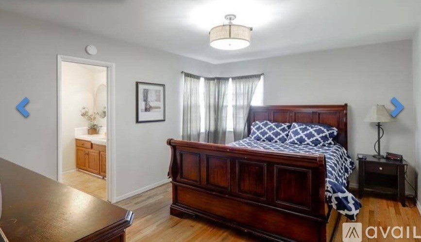 A bedroom with a large bed and a wooden dresser.