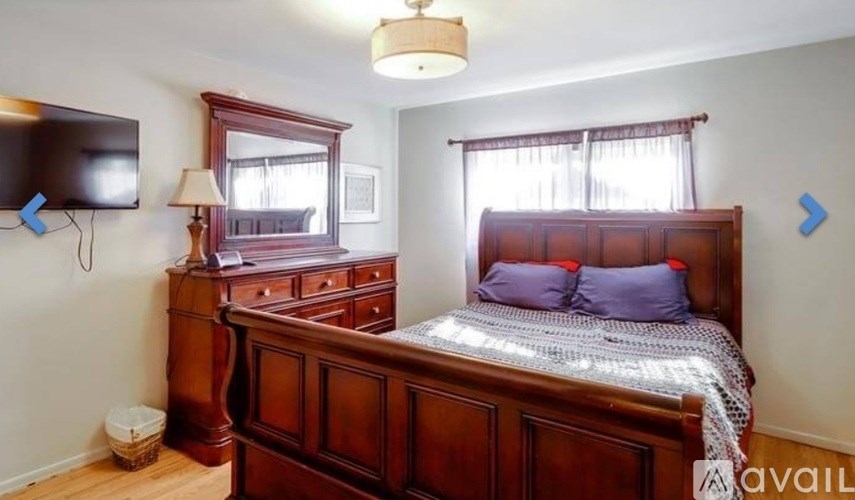 A bedroom with a large bed and a wooden dresser.