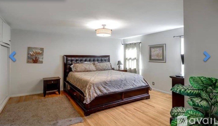 A bedroom with a large bed and a rug on the floor.