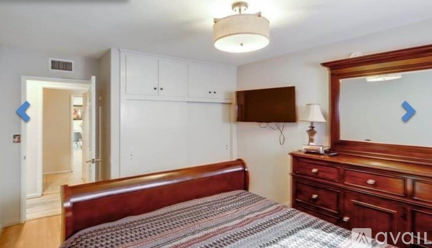 A bedroom with a bed, dresser, and mirror.