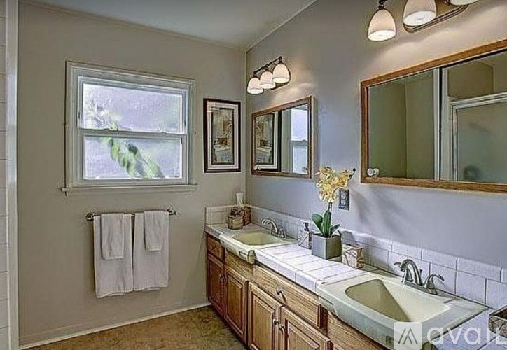 A bathroom with a window, two sinks, and a mirror.