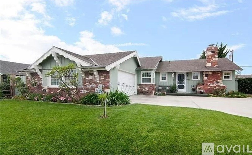 A house with a green lawn and a tree in front of it.