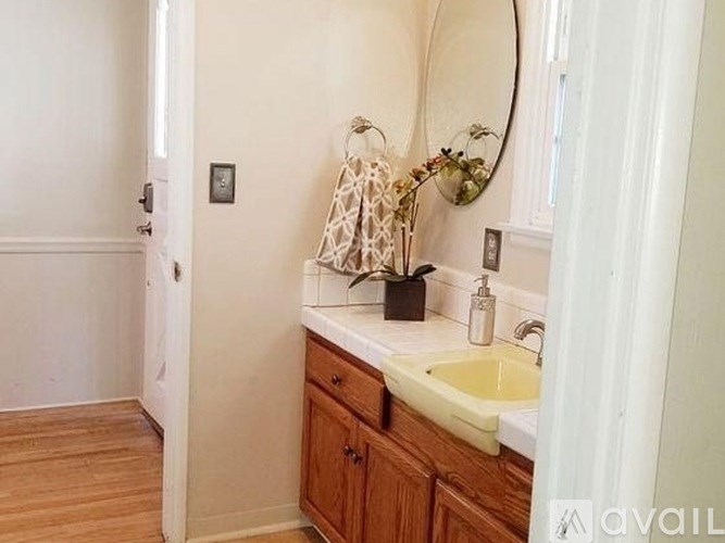 A bathroom with a sink, mirror, and wooden floors.