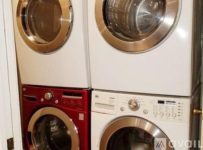 Two washing machines, one red and one white, are stacked on top of each other.