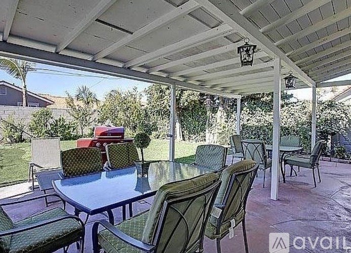 A patio with a table and chairs under a roof.