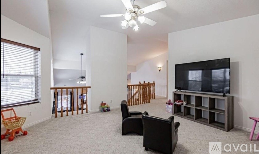 A living room with a television, two chairs, a table, and a shelf.