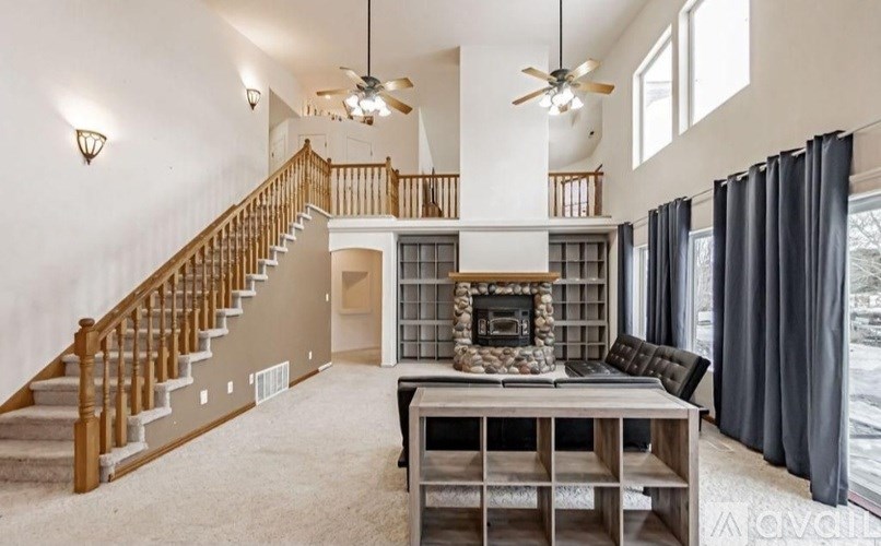 A spacious living room with a staircase and a fireplace.