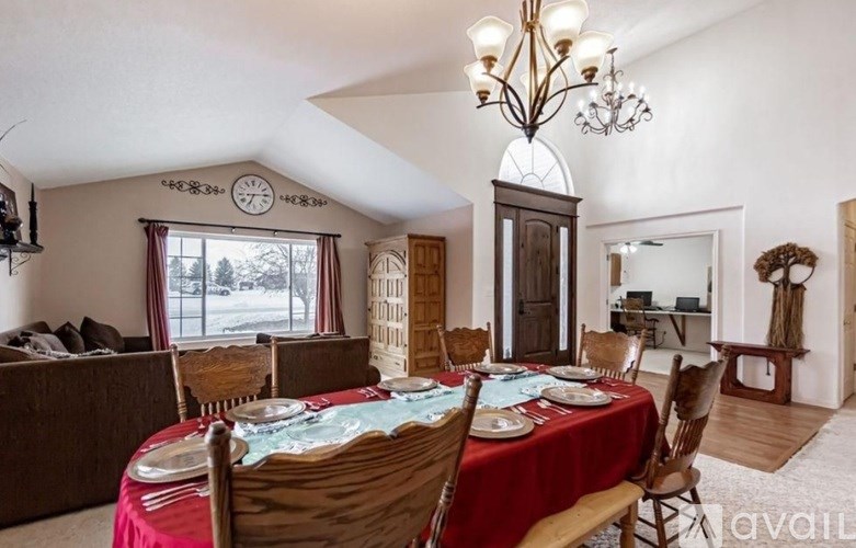 A dining room with a red tablecloth and wooden chairs.