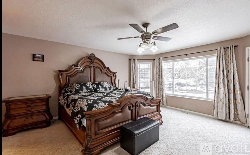 A bedroom with a large bed and a ceiling fan.