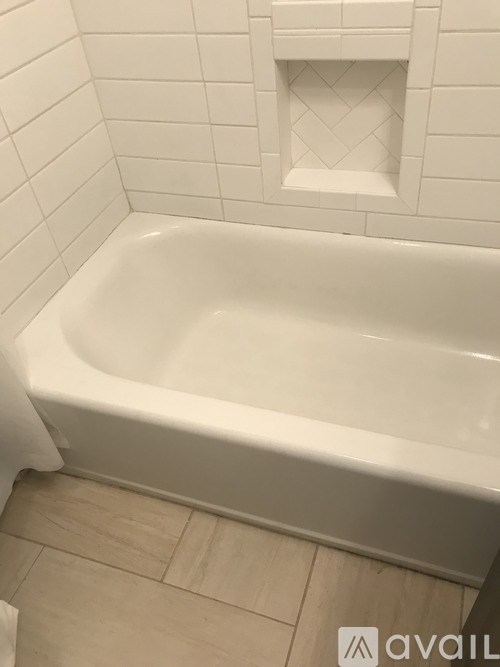 A white bathtub in a bathroom with a white tiled wall.
