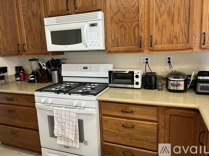 A kitchen with a white stove and wooden cabinets.