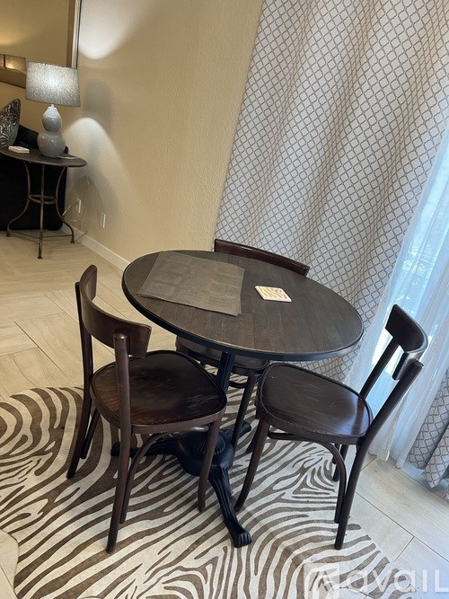 A zebra print rug sits under a round glass table with two chairs.