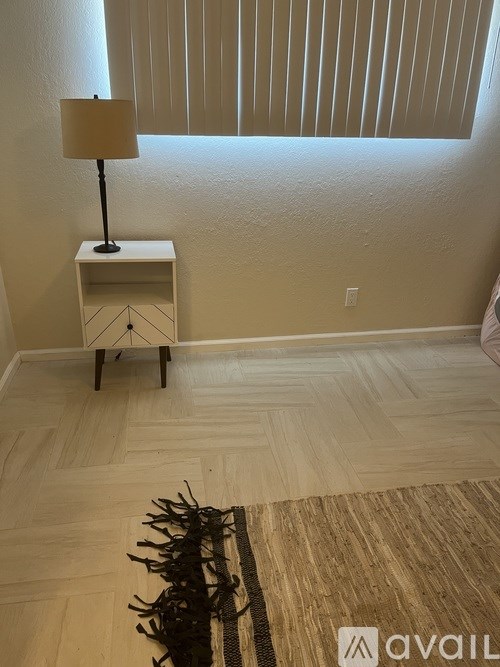 A lamp on a small table in a room with a rug on the floor.