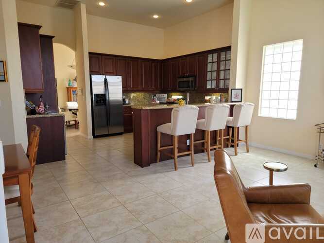 A kitchen with a refrigerator, microwave, and oven, with a dining table and chairs in the foreground.
