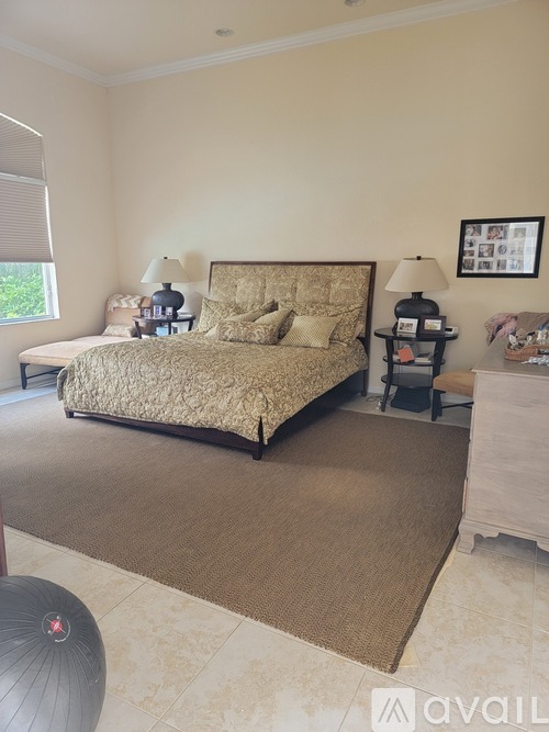 A bedroom with a large bed and a lamp on a side table.
