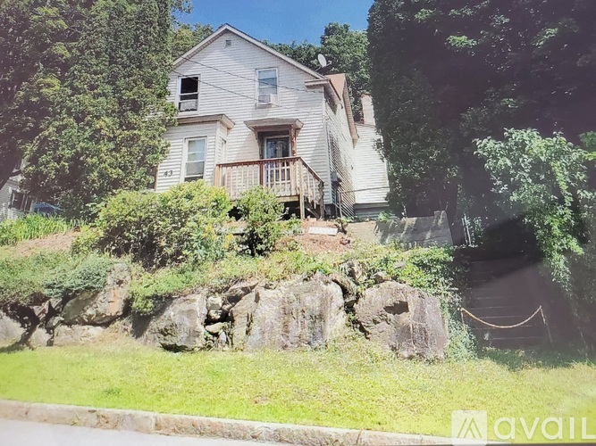 A house with a porch and a tree in front of it.
