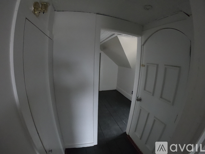 A hallway with a white door and a white wall.