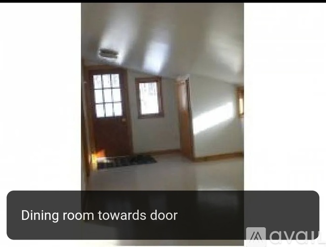 A dining room with a table and chairs towards the door.