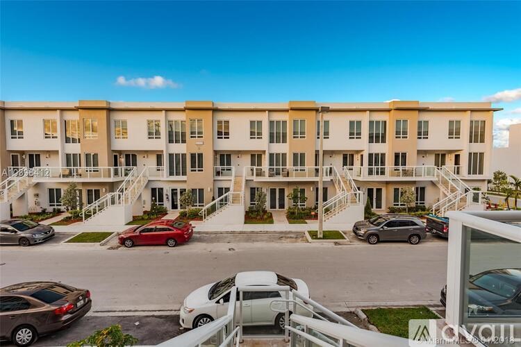 A multi-story apartment building with a parking lot in front.