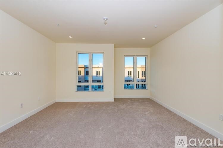 A spacious room with a large window and carpeted floor.