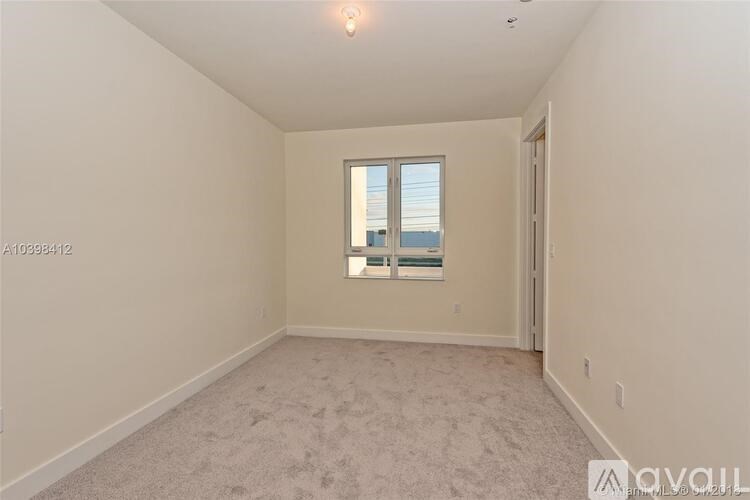 A room with a carpeted floor and a window overlooking the ocean.