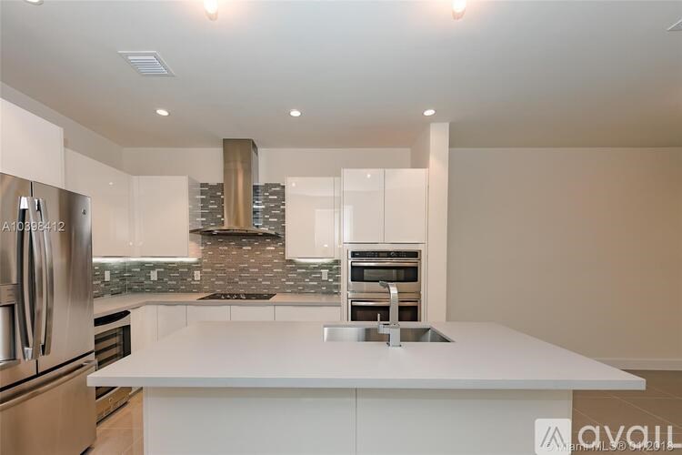 A modern kitchen with a white countertop and stainless steel appliances.