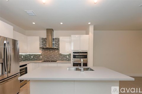 A modern kitchen with a white countertop and stainless steel appliances.