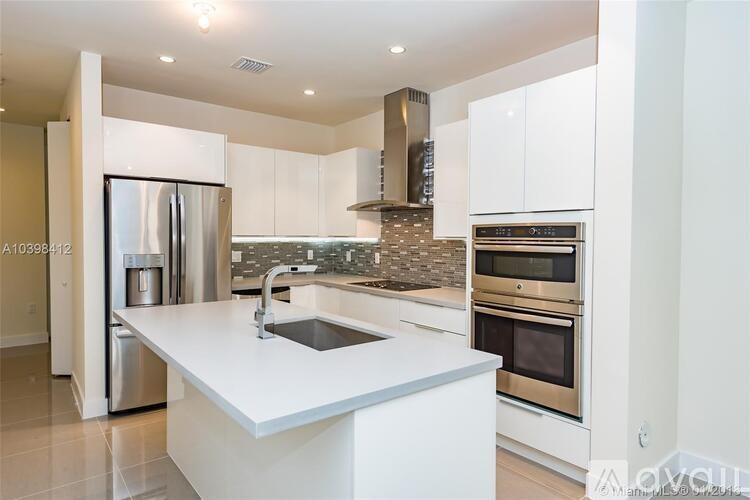 A modern kitchen with a white countertop and stainless steel appliances.