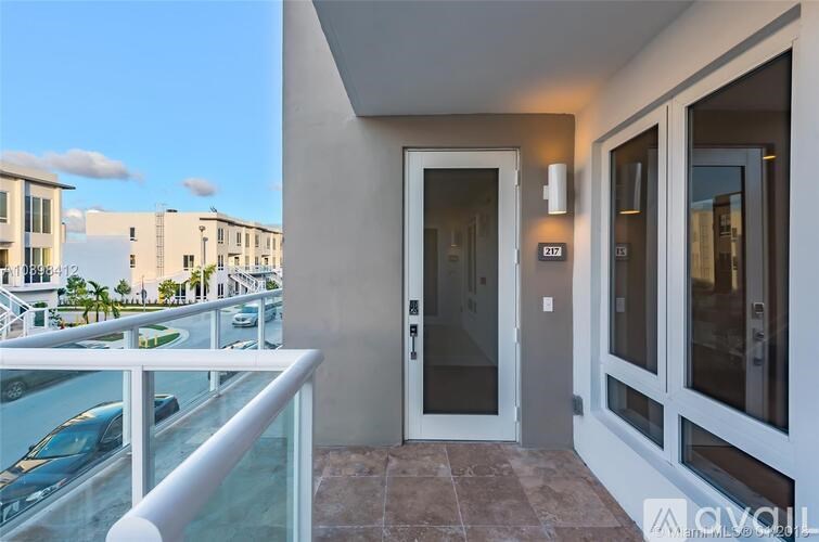 A balcony with a glass railing and a view of a building across the way.