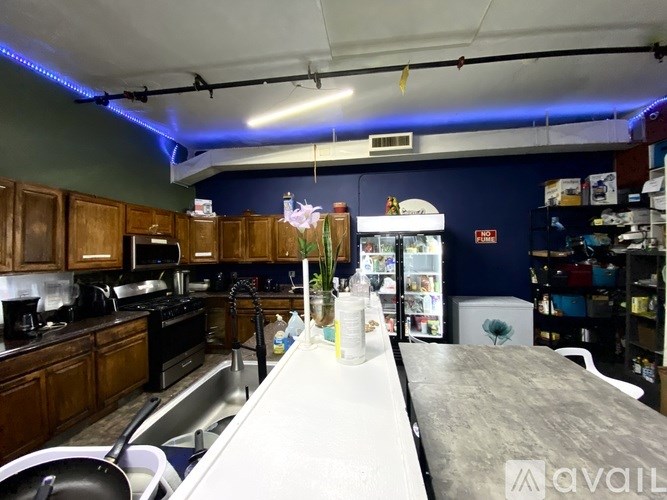 A kitchen with a long counter and a refrigerator in the background.