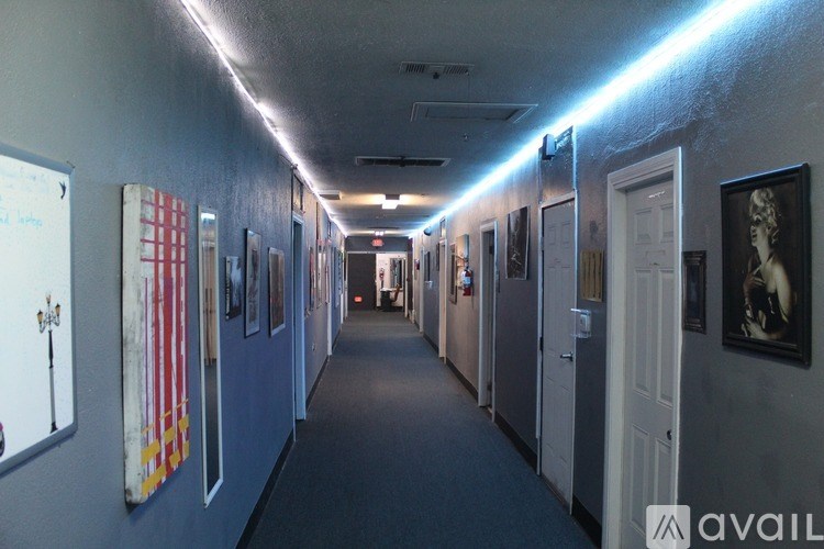 A long hallway with doors on both sides and pictures on the wall.