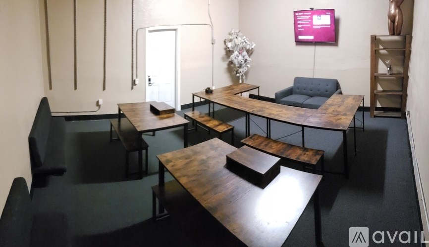 A room with a black floor and furniture, a white wall, and a TV screen.