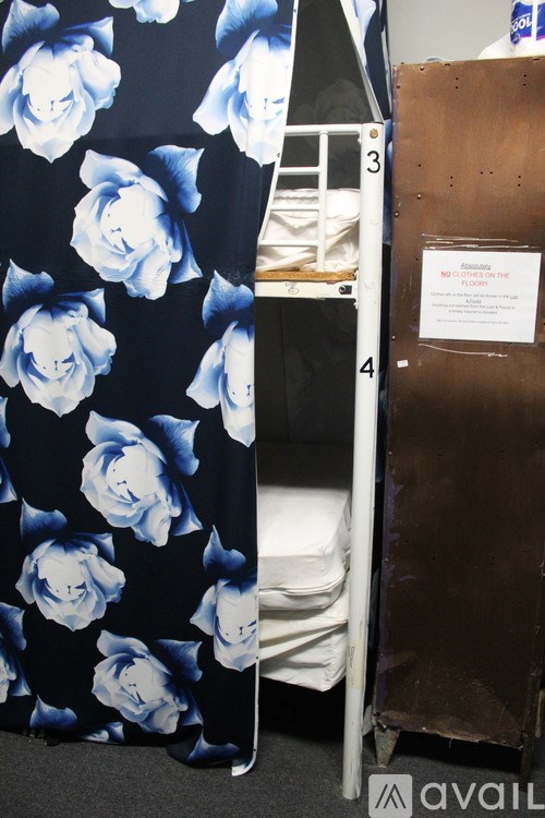 A bunk bed with a floral print sheet and a sign on the side table.