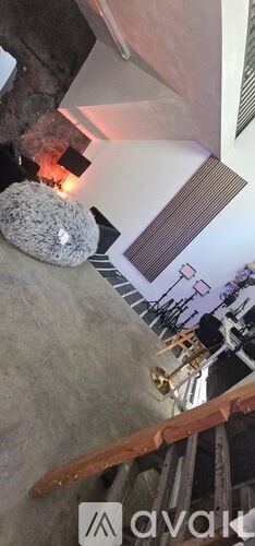 A cat is sitting on the floor next to a wall with a poster on it.