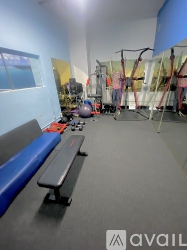 A gym with a bench, weights, and exercise equipment.