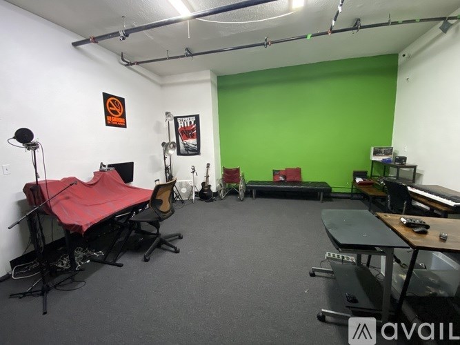 A room with a green screen and a red chair.