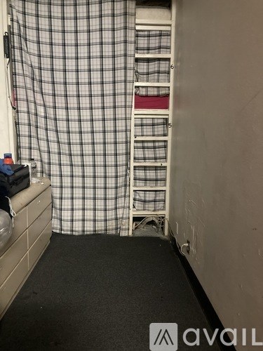 A room with a checkered shower curtain and a black mat on the floor.