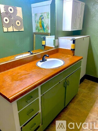 A bathroom with green cabinets and a wooden counter top.