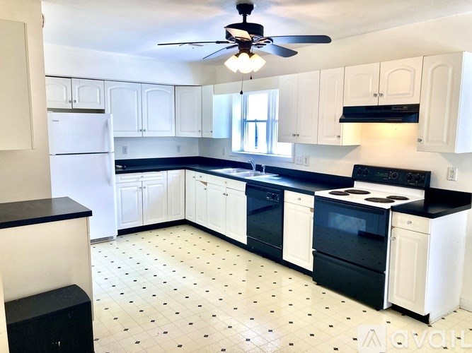 A kitchen with black and white appliances and a ceiling fan.