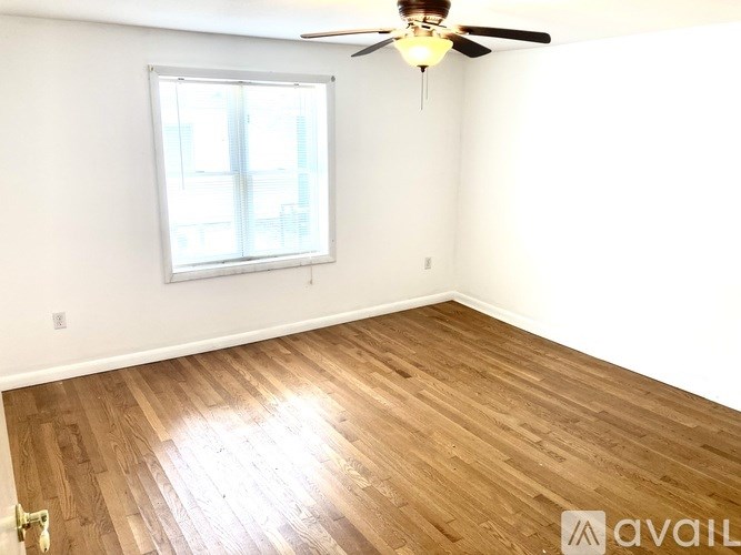 A room with a ceiling fan and a window with a view of a building outside.