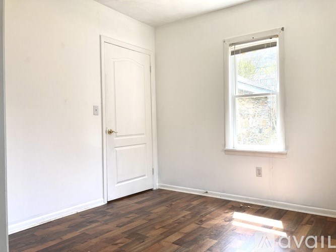 A room with a white door and a window with a view of a house.