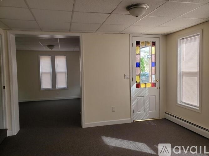 A room with a stained glass door and carpeted floor.