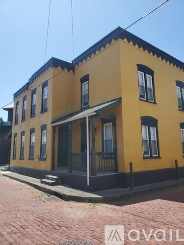 A yellow house with a black railing and a black awning.